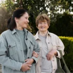 Two young women walking arm in arm outdoors.