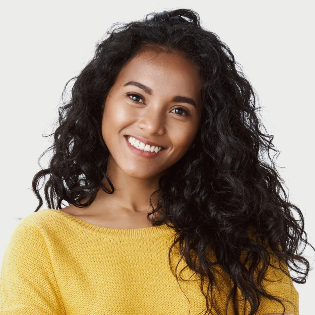 Portrait of woman with curly hair and yellow sweater.