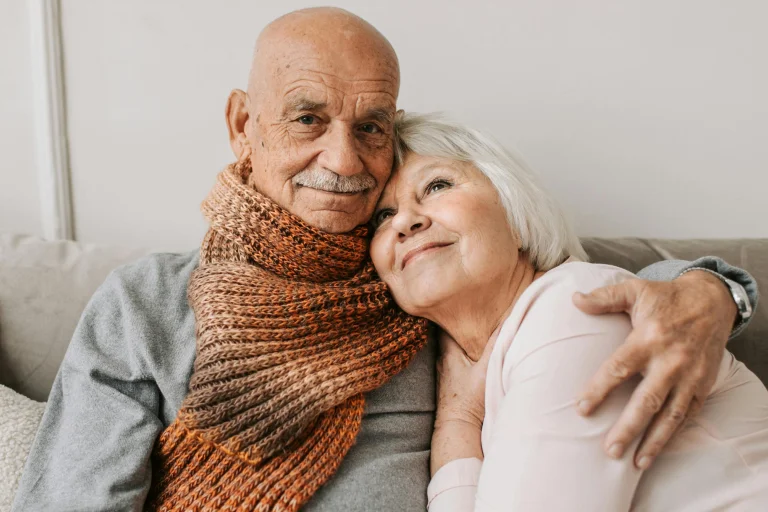 Elderly couple embracing in cozy sweaters.
