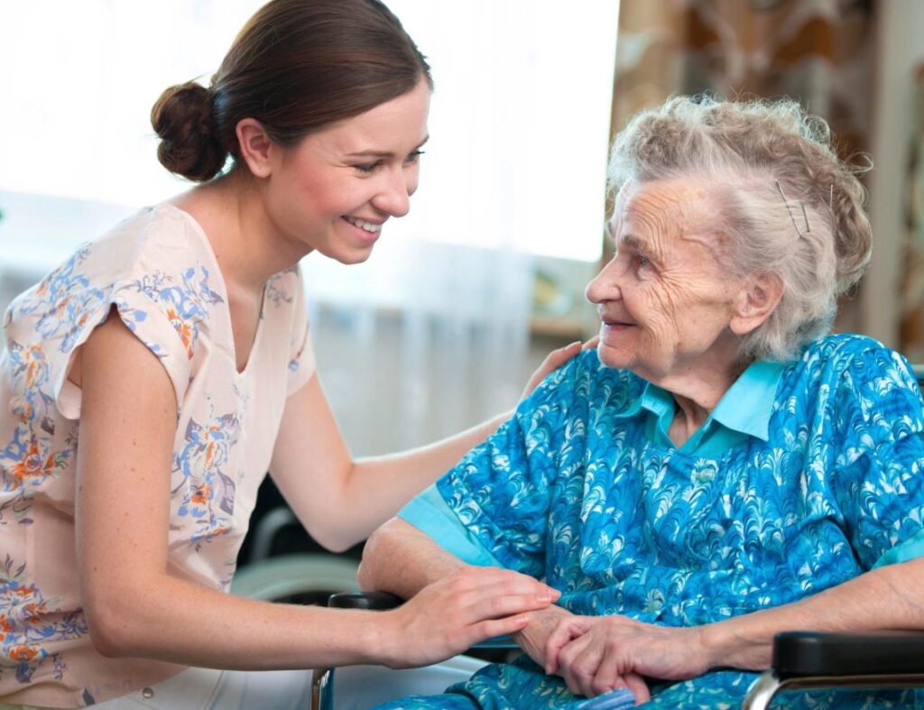 Young woman offering support to senior in a wheelchair
