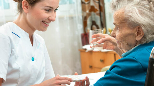 Nurse assisting an elderly patient with medication.