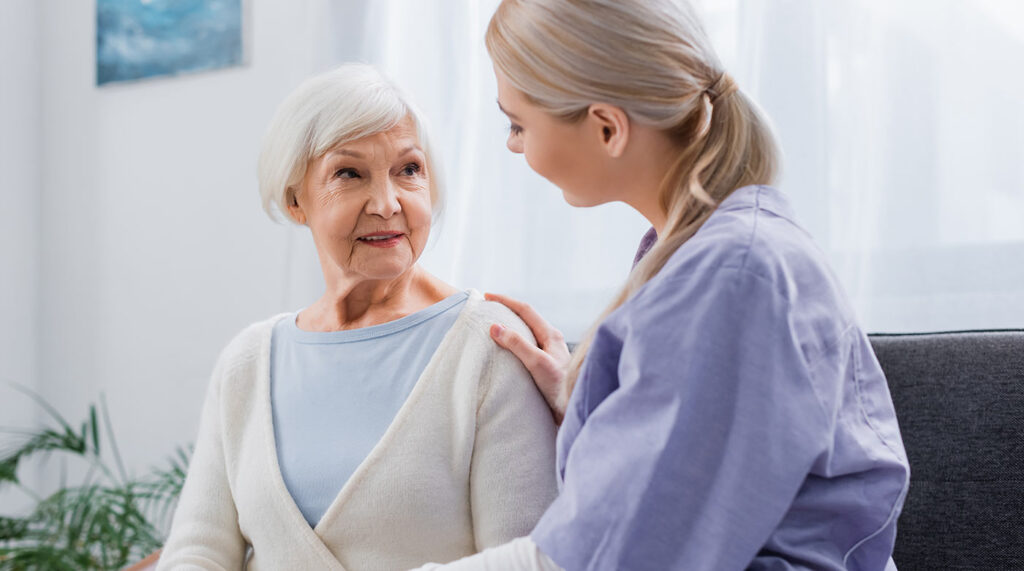 Healthcare worker assisting senior with shoulder check.