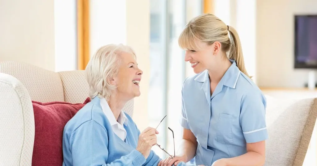 Staff member conversing closely with elderly woman.