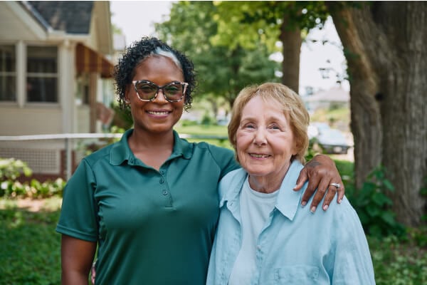 Caregiver standing with senior outdoors.