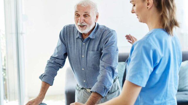 Physiotherapist helping senior man for walking