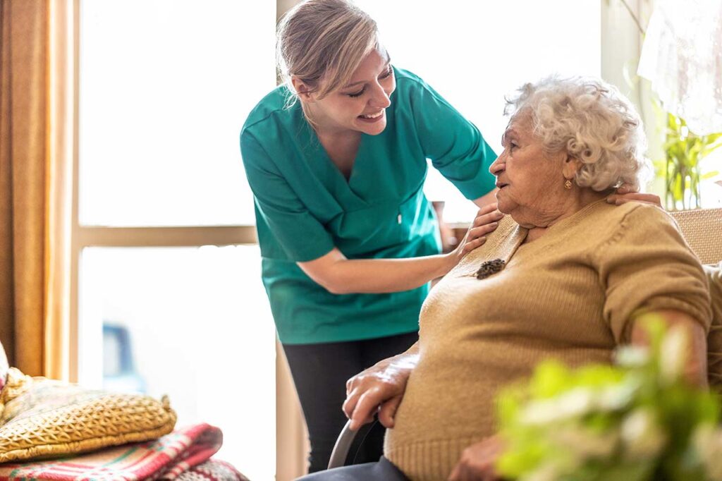 Nurse gently comforting elderly woman on sofa.