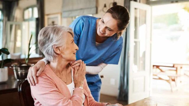 Nurse helping elderly woman at home.
