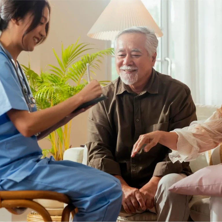 Nurse chatting and giving care to senior man indoors.